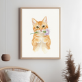 Framed watercolor print of an orange tabby cat holding a purple flower in its mouth against a minimalist white background.