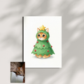A framed print displaying a watercolor portrait of a ginger cat wearing a Christmas tree costume against a white backdrop.