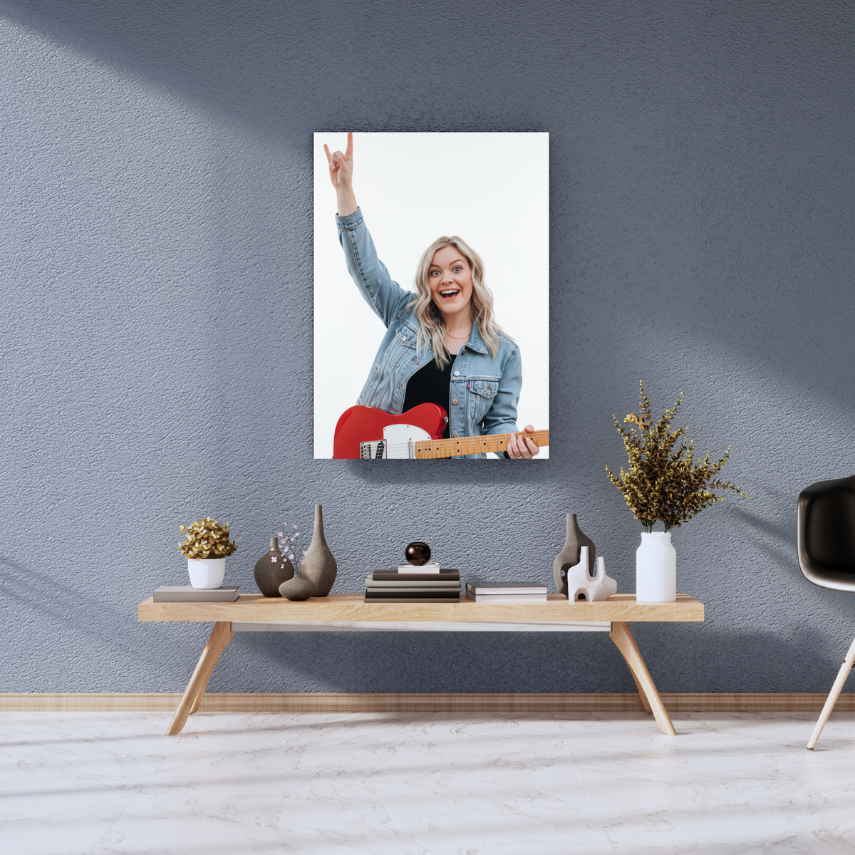Framed print of a woman in a denim jacket playing a red guitar and giving a rock-on sign against a