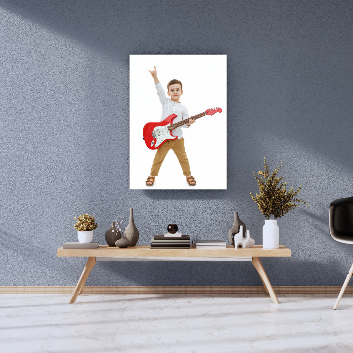 Framed print of a young boy in a white shirt playing a red guitar, shown on a living room wall