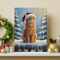 Framed oil painting portrait of an orange tabby cat wearing a Santa hat, set against a snowy winter wonderland background.