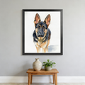 Framed watercolor print of a German Shepherd against a white background, displayed on a wall above a wooden side table.