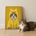 Framed print of a tabby cat in a fuzzy yellow duck hoodie, matching a real cat lying on the floor