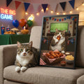 A framed print of a realistic, painterly portrait showing a tabby cat eating chicken wings in a festive game-day setting.